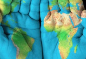 A photo of two hands with palms painted with a colorful map of the globe.