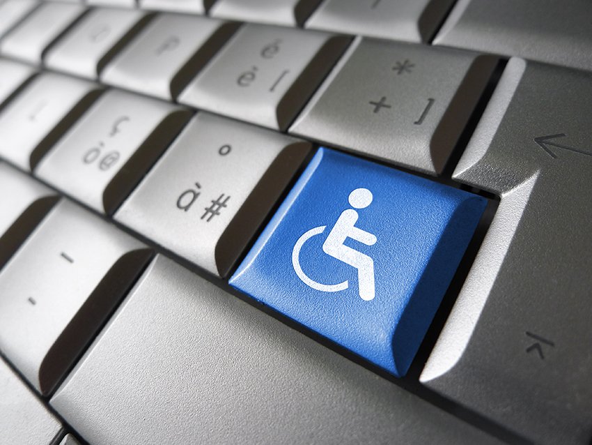 Close up of a computer keyboard with a one blue colored key with a white wheelchair icon.