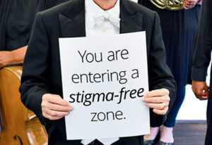conductor holding a placard: you are entering a stigma-free zone